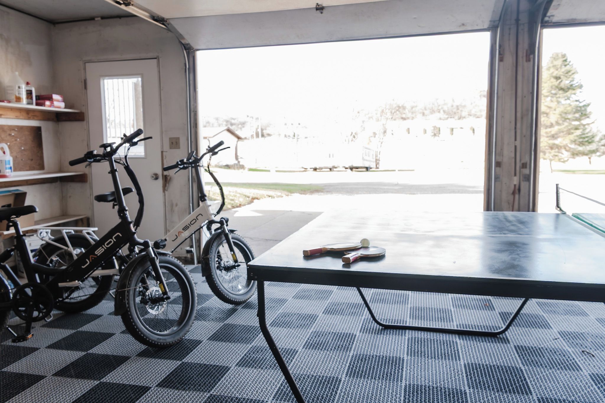 Eine Garage mit zwei Fahrrädern, einem Tischtennisplatten und einem Schachbrettboden.