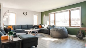 A modern living room with a sectional sofa, a coffee table, and a bean bag. - KwikStay: The Small-Town Ranch Style Home (Loganville)