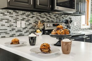 Una cocina moderna con encimera blanca, salpicadero de azulejos blanco y negro y horno de acero inoxidable.