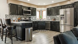A modern kitchen with dark cabinetry, stainless steel appliances, and a central island. - KwikStay: The Small-Town Ranch Style Home (Loganville)