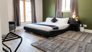 A modern bedroom with a large bed, a small bedside table with a lamp, and a view of the outdoors through a window. - KwikStay: The Small-Town Ranch Style Home (Loganville)