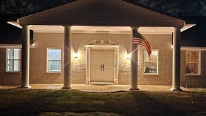 Une maison à deux étages, construite en briques, avec un porche abrité, un garage et une porte d’entrée.