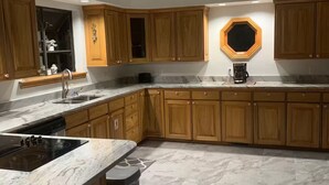 Une cuisine moderne avec des meubles en bois, une cuisinière encastrée et un plan de travail en marbre.