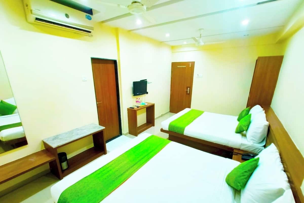 Quarto de hotel com duas camas, uma televisão, uma mesinha e um banco.