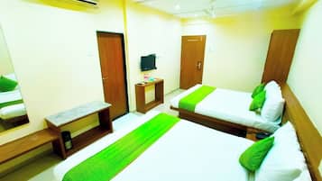 Quarto de hotel com duas camas, uma televisão, uma mesinha e um banco.