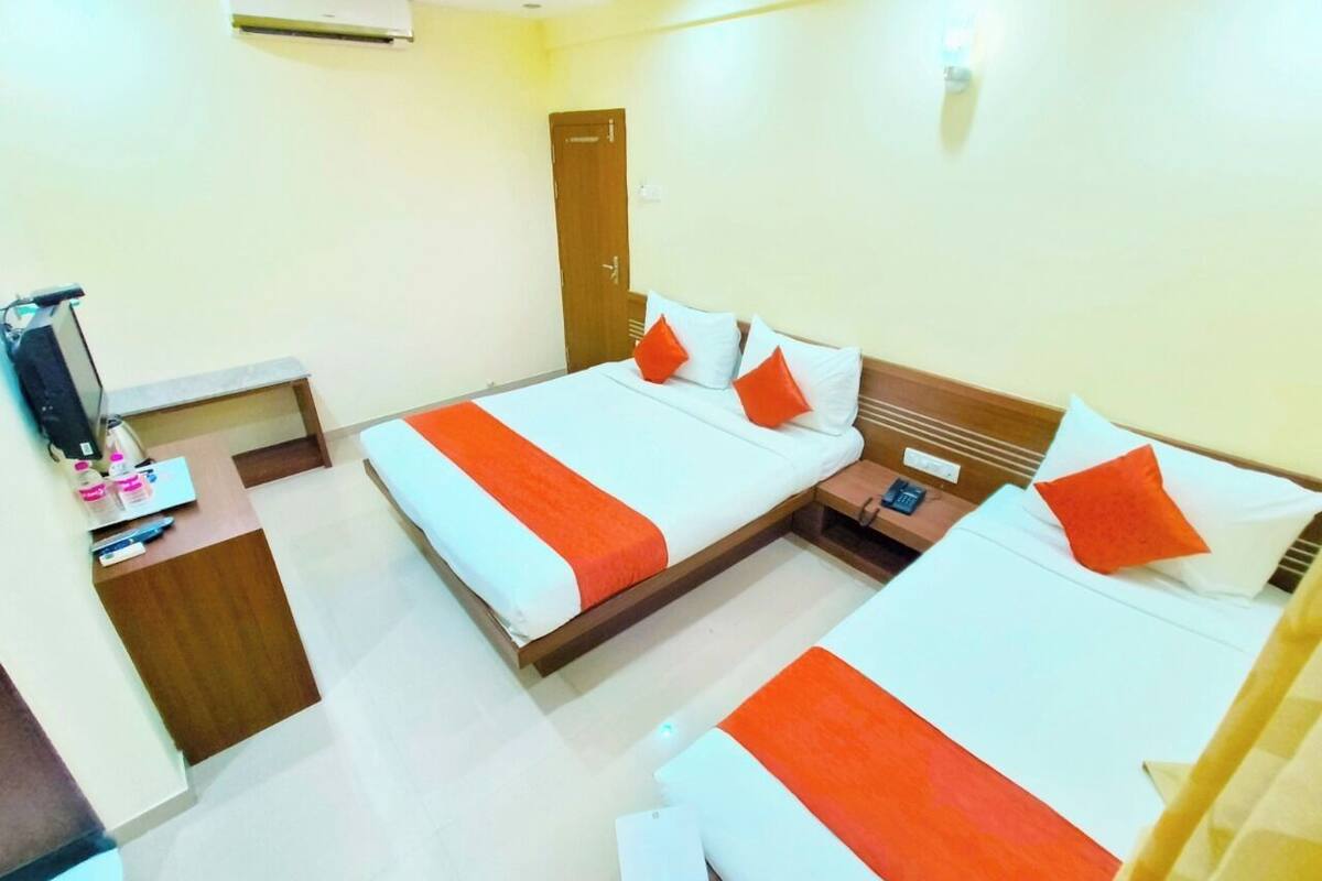 Quarto de hotel com duas camas, uma escrivaninha, um guarda-roupa e uma televisão.