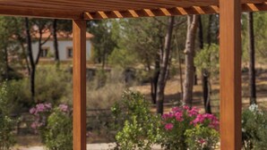 A wooden pergola with a cushioned bench and a white cushion. - 31-Basement apartment - Villa Natura Bliss (Alcácer do Sal)