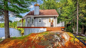 A lakeside cabin with a deck, a chimney, and a view of the lake. - Unforgettable Extended Stays In Beauce At The Lake (Saint-Victor)