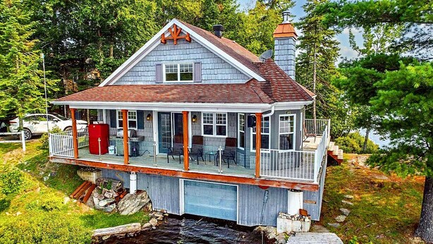 A two-story house with a balcony, a chimney, and a dock extending into a body of water. - Unforgettable Extended Stays In Beauce At The Lake (Saint-Victor)