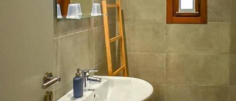 A bathroom with a white sink, a wooden ladder, and a window with a wooden frame.