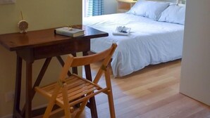 A bedroom with a bed, a desk with a chair, a window with curtains, and a nightstand with a lamp. - B&B VILLA ELISA (Motta di Livenza)