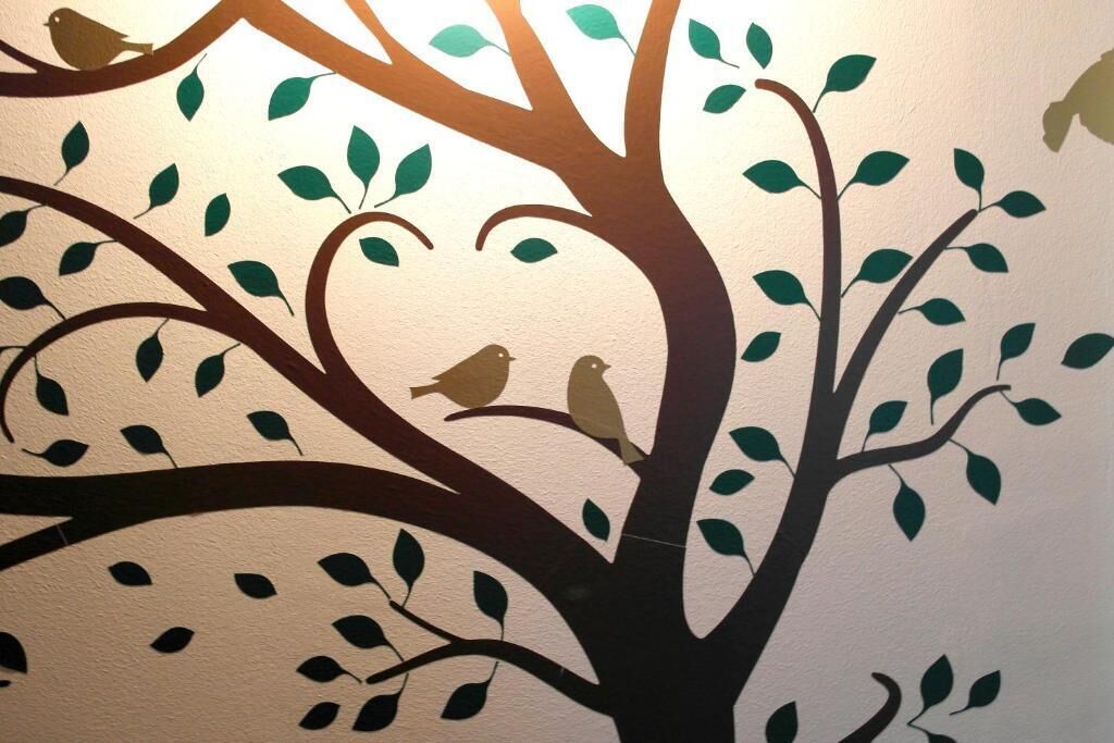 A wall with a tree silhouette and birds.