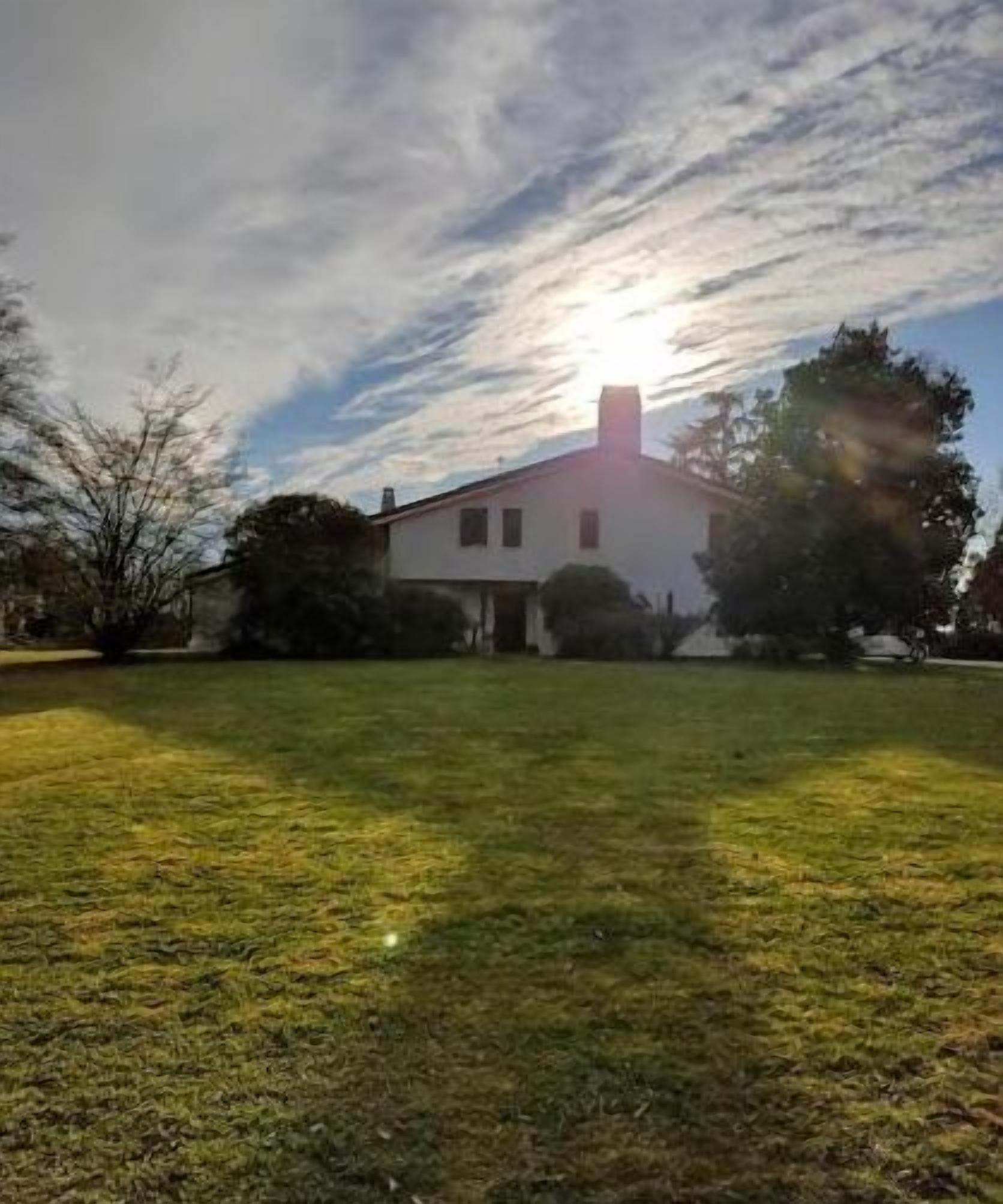A single-story house with a white exterior and a chimney, surrounded by a well-maintained lawn and trees.