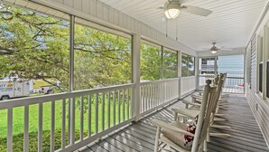 A covered porch with white railings, wooden flooring, and ceiling fans. - Cocktail Time-6Br/3.5BA in Ocean Drive-Pet Friendly (North Myrtle Beach)