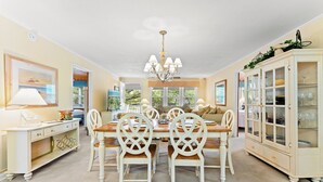 A dining room with a chandelier, white chairs, a wooden table, a cabinet with glass doors, and a lamp. - Cocktail Time-6Br/3.5BA in Ocean Drive-Pet Friendly (North Myrtle Beach)