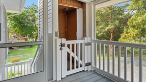 A covered porch with a white railing, a wooden door, and a view of a green lawn and trees. - Cocktail Time-6Br/3.5BA in Ocean Drive-Pet Friendly (North Myrtle Beach)