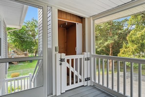 A covered porch with a white railing, a wooden door, and a view of a green lawn and trees. - Cocktail Time-6Br/3.5BA in Ocean Drive-Pet Friendly (North Myrtle Beach)
