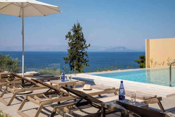 A poolside area with lounge chairs, a table, and an umbrella.