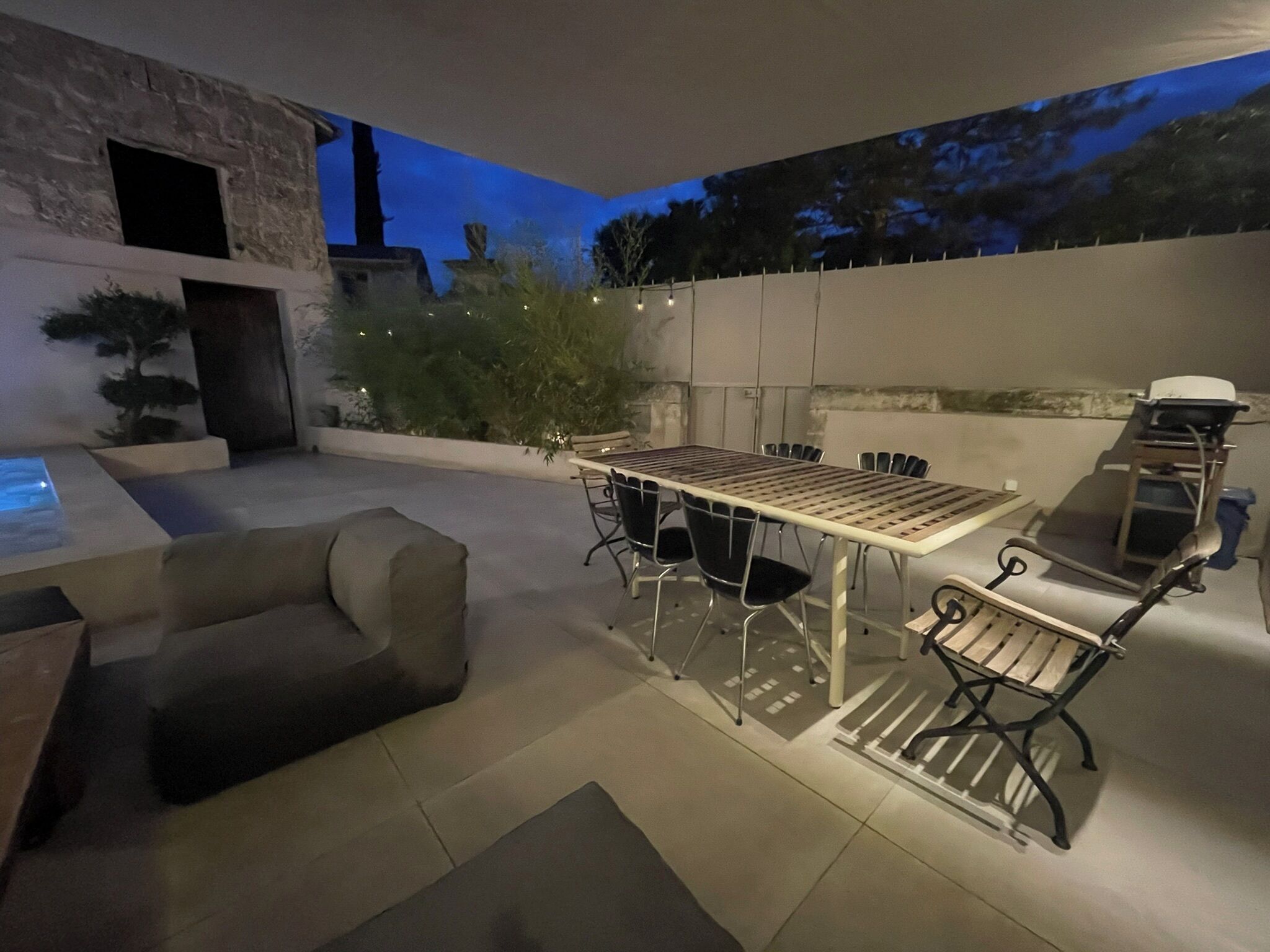 Eine Terrasse im Freien mit Esstisch, Stühlen, Grill und einer Couch.
