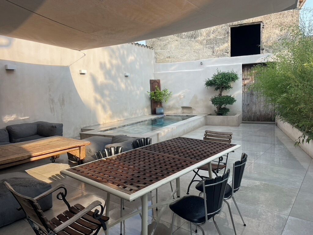 Un patio al aire libre con piscina, zona de estar y plantas en macetas.