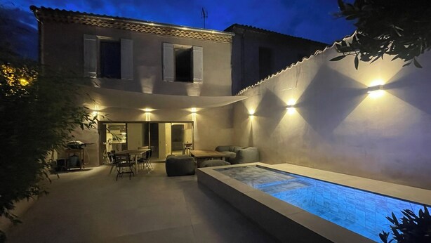 A two-story house with a swimming pool, outdoor seating, and a well-lit patio area. - Air-conditioned 3-bedroom house in quiet location with swimming pool (Junas)