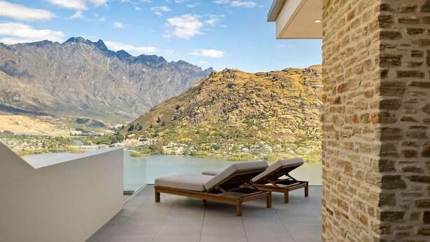 Un balcon avec deux fauteuils en bois donnant sur une vue sur la montagne.