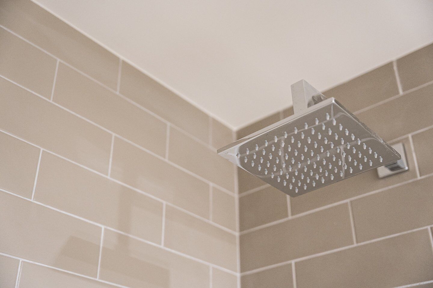 A showerhead mounted on a tiled wall.