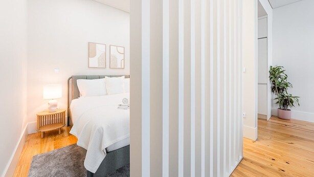 A modern bedroom with a bed, bedside table, lamp, and artwork on the wall.