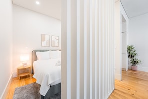 A modern bedroom with a bed, bedside table, lamp, and artwork on the wall. - GuestReady - Porto's Lovely Retreat (Porto)