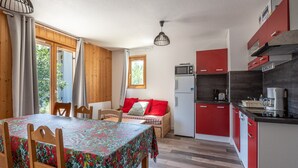 Eine kleine Küche mit Essbereich, Holzschränken und einem fenster mit Vorhängen.