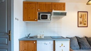 Une cuisine compacte dotée de meubles en bois, d’un four à micro-ondes, d’un lave-vaisselle et d’un réfrigérateur.