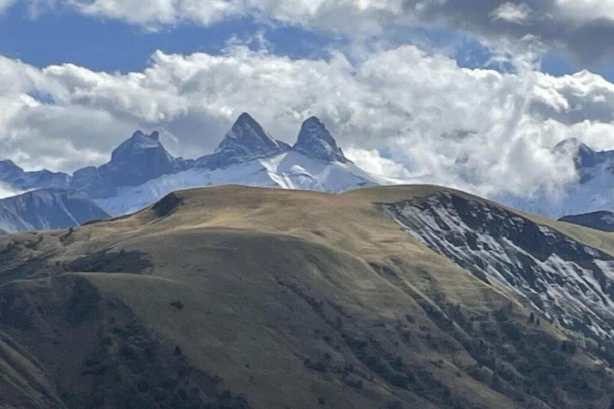 Un paysage montagneux aux sommets enneigés, sous un ciel dégagé.