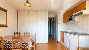 Une cuisine compacte comprenant une table à manger, des placards en bois et un four à micro-ondes.