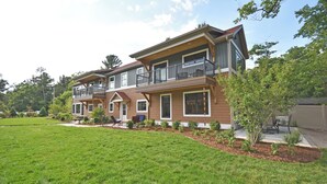 Ein zweistöckiges Haus mit großem Vorgarten, einem Balkon im zweiten Stock und einer kleinen Terrasse.