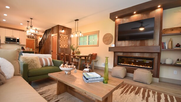 Ein modernes Wohnzimmer mit einem grünen Sofa, einem Holztisch und einem Kamin.