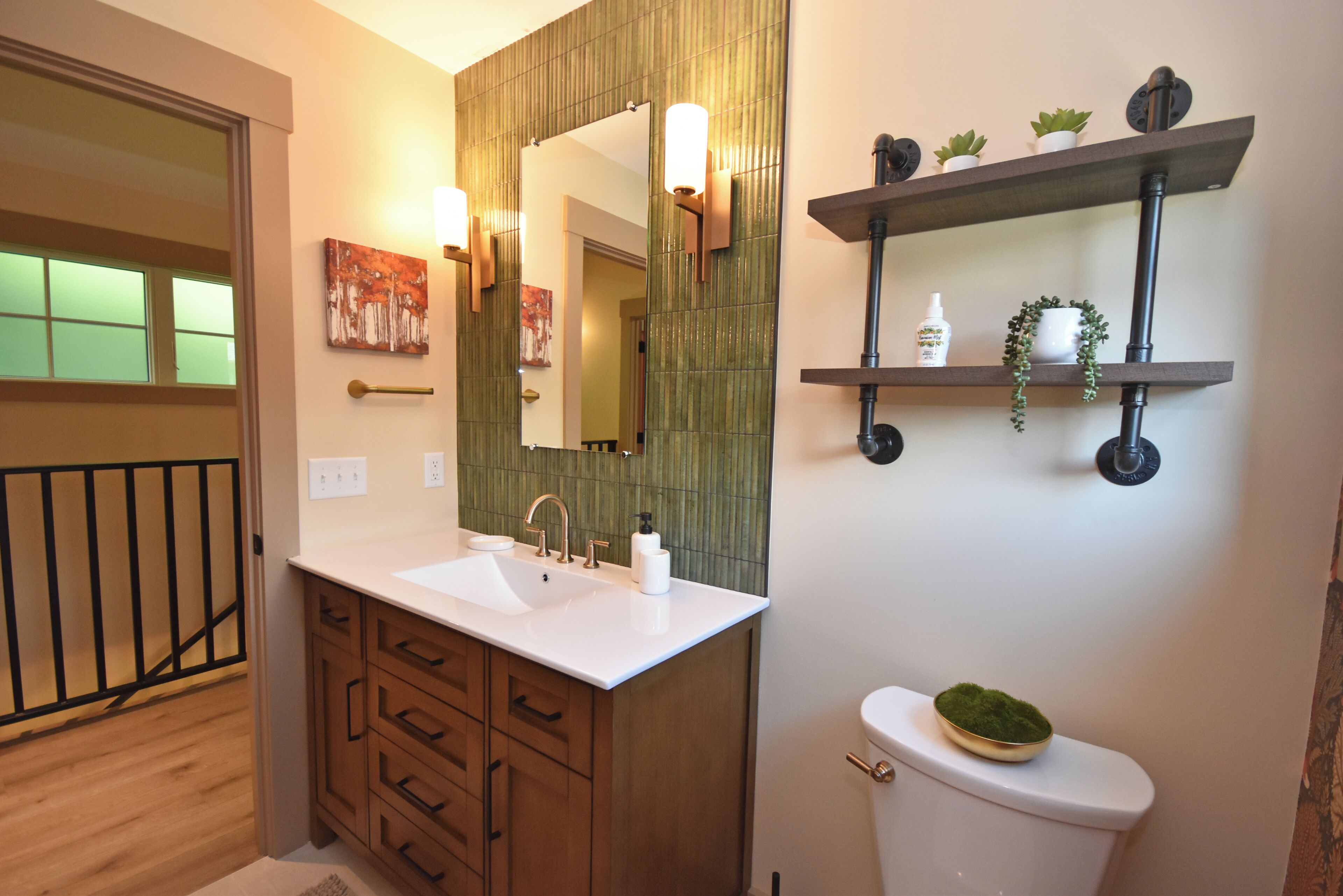 Un baño con tocador de madera, un espejo grande, un inodoro y estantes con plantas.