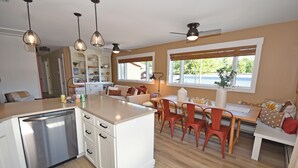 A modern kitchen with a dishwasher, white cabinetry, and a dining area with a table and chairs.