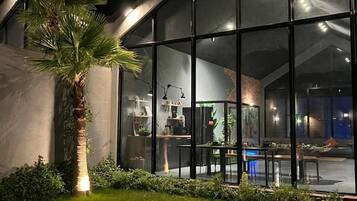 A modern house with large glass windows, a well-maintained lawn, and a palm tree.