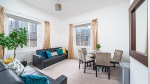 Ein modernes Wohnzimmer mit Sofa, Esstisch, Stühlen und Fernseher.
