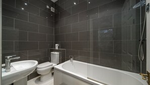 Ein modernes Badezimmer mit Badewanne, Toilette und Waschbecken.