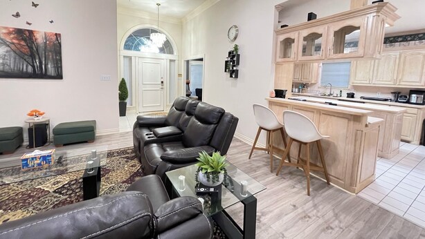 A modern living room with a leather sofa, a glass coffee table, and a view of the kitchen area. - Charming 3-bedroom house near AT&T Stadium, Six Flag, DFW Airport (Bedford)