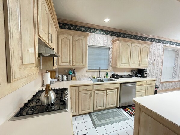 Una cocina con armarios de madera, estufa a gas, un lavabo y lavavajillas.