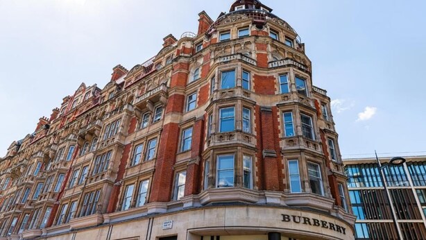 A corner building with the 'BURBERRY' sign, featuring a classic architectural style with multiple windows and a brick facade.