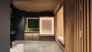 A modern hotel lobby with a reception desk, a green wall, and a seating area.