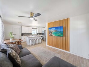Una sala de estar moderna con un sofá, un comedor, una cocina y un ventilador de techo.