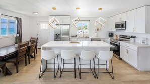 Una cocina moderna con una isla central, armarios blancos y taburetes de bar.