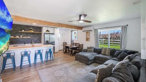 A modern living space with a kitchen, dining area, and a large sofa. - Oahu Oceanfront Getaway (Hauula)