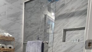 Une salle de bain avec une douche à parois de verre, des toilettes et un tapis sur lequel est écrit le mot « RELAX ».