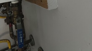 Un chauffe-eau avec une étiquette jaune, une planche de bois et un tuyau en métal.