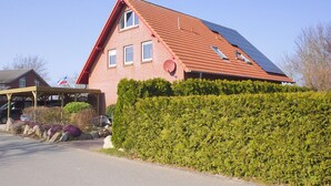 Una casa de ladrillo rojo con techo inclinado, paneles solares y un porche cubierto.